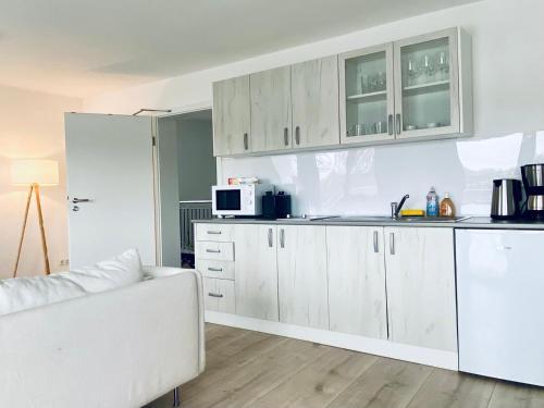 a kitchen with white cabinets and a white couch at Das Bootshaus in Seeon