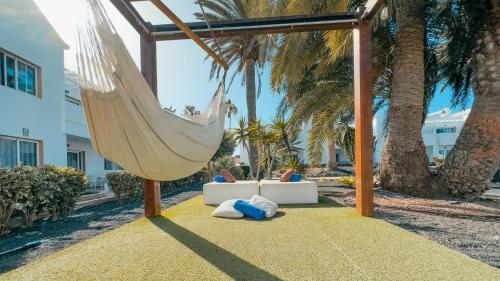 a hammock and a couch in a resort with palm trees at Labranda Corralejo Village in Corralejo