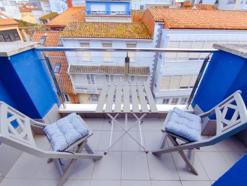 2 sillas en un balcón con edificios en el fondo en Vivienda Novo Betanzos, en Betanzos