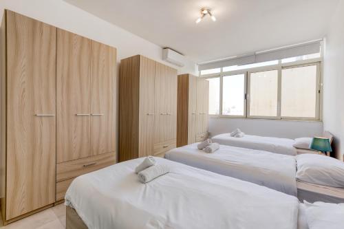una camera con 3 letti, un armadio e finestre di De Redin a Sliema