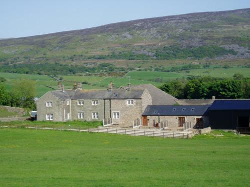 a large house in a field with a hill in the background at Knotts Farm Holiday Cottages in Lancaster