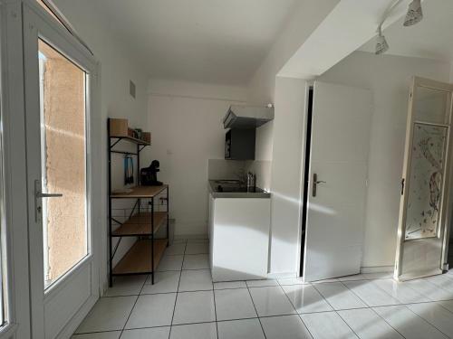 een witte keuken met een koelkast en een raam bij T1 bas de villa in Ollioules