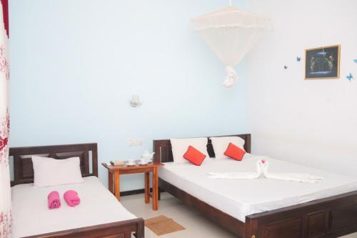 two beds in a room with pink slippers on them at For Backpackers -Close to the National Park- in Udawalawe