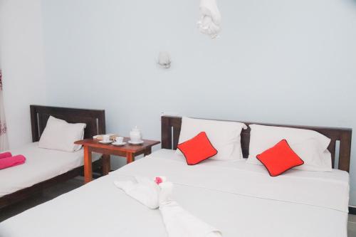 a room with two beds with red pillows and a table at For Backpackers -Close to the National Park- in Udawalawe
