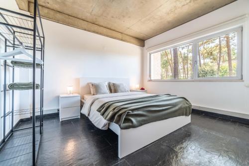 a white bedroom with a bed and a window at Villa Jasmine in Aroeira