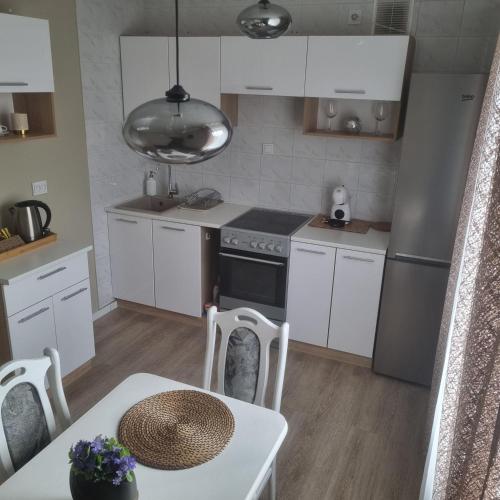 a kitchen with white appliances and a table and a table and chairs at Holiday Apartments 10 in Druskininkai