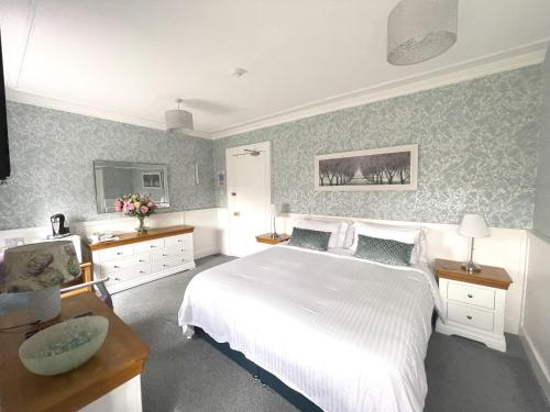 a bedroom with a large white bed and green wallpaper at Kilmory House in Lochgilphead