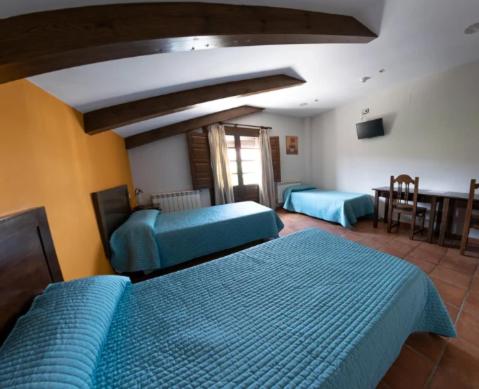 1 dormitorio con 2 camas azules y mesa en El Foro de Rueda, en Rueda