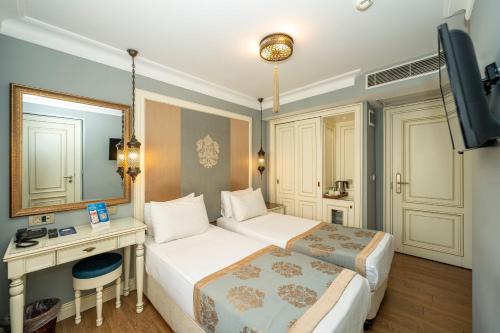 a bedroom with two beds and a desk and a mirror at Raymond Blue Hotel in Istanbul