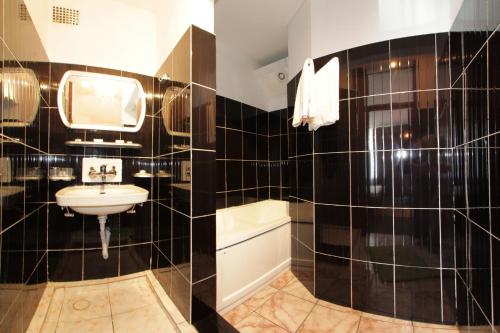 La salle de bains est pourvue de murs carrelés noirs et d'un lavabo. dans l'établissement Complex Mamaia - HISTRIA, à Mamaia