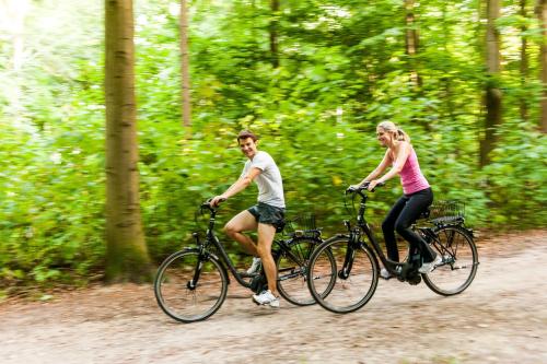 a man and a woman riding bikes down a road at Hotel Birke - Appartments Waldesruh in Kiel