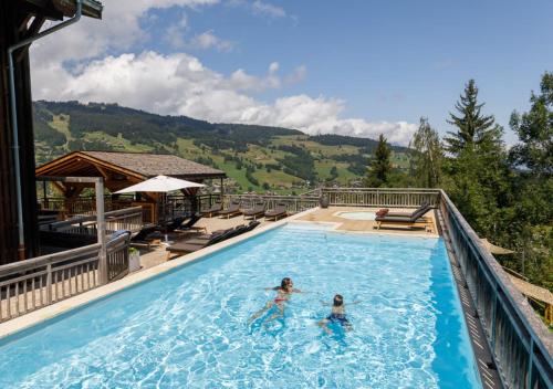 dos personas en una piscina en un complejo en Hôtel L'Arboisie en Megève
