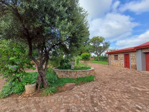 un vialetto di mattoni con un albero e un edificio di At Ease Road Lodge a Zeerust