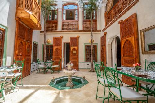 una habitación con mesas, sillas y una fuente en Riad Chez Henriette en Marrakech