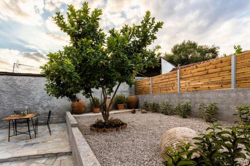 a courtyard with a tree and a table and chairs at Valira Cozy Maisonette - Relaxing Vibes Getaway in Valíra