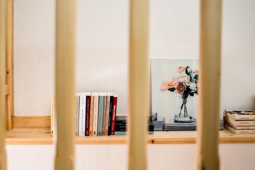 a shelf with a vase of flowers and books at Valira Cozy Maisonette - Relaxing Vibes Getaway in Valíra