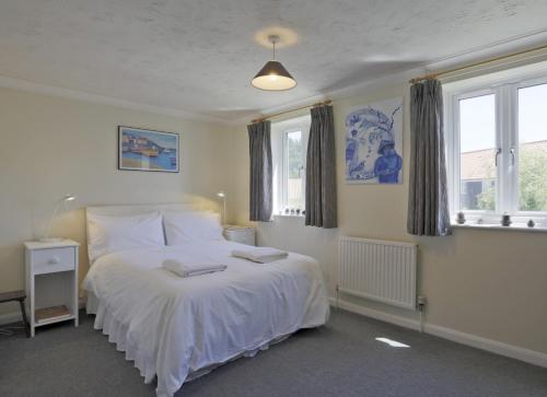 a bedroom with a white bed and two windows at Sparrows, Wangford nr Southwold in Wangford