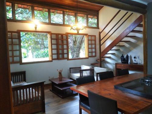 uma sala de jantar com mesa, cadeiras e janelas em Casa de Campo Pampulha em Belo Horizonte