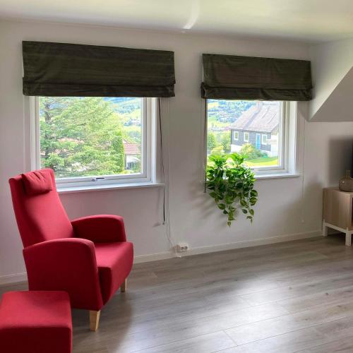 a living room with a red chair and two windows at Store Ringheim Apartment - Villa Hjadlane in Vossevangen