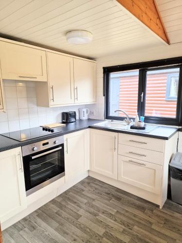 a kitchen with white cabinets and a sink at Beaver 1 HuntersMoon-warminster-Wiltshire in Warminster