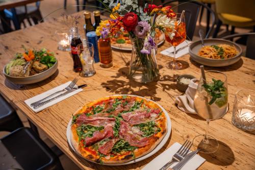 a wooden table with a pizza and plates of food at Scheck Hotel in Munich