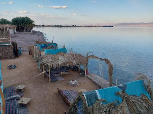 a group of tables and chairs on the shore of a body of water at Perry’s Island Camp Al Mezina in Nuweiba