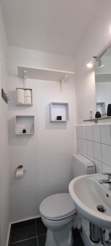 La salle de bains blanche est pourvue de toilettes et d'un lavabo. dans l'établissement Gemütliches Nest zum Wohlfühlen, à Osnabrück