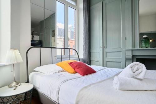 a bedroom with a bed with white sheets and colorful pillows at Lille Saint Maurice - Nice and functional studio in Lille