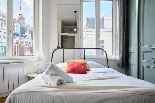 a bedroom with a bed with white sheets and a window at Lille Saint Maurice - Nice and functional studio in Lille