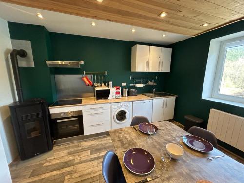 - une cuisine avec une table en bois et des murs verts dans l'établissement Le Travexin, à Cornimont