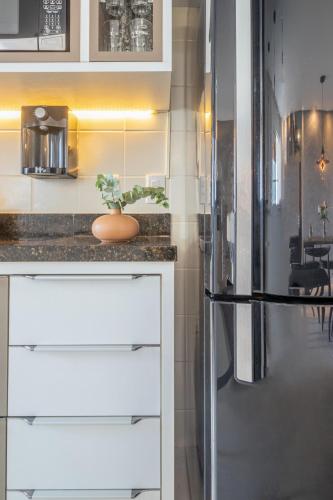a kitchen with white cabinets and a refrigerator at PALMAS EXPERIENCE - APARTAMENTO BRISA, no centro, vista lago! in Palmas