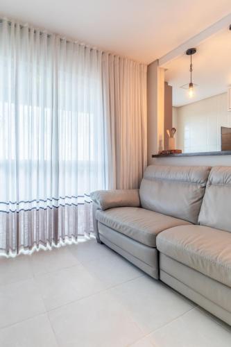 a living room with a couch in front of a window at PALMAS EXPERIENCE - APARTAMENTO BRISA, no centro, vista lago! in Palmas