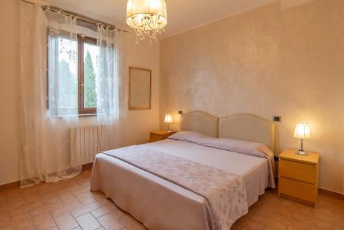 Un dormitorio con una cama y una ventana y una lámpara de araña. en Star View Apartment with pool, en Castiglioncello