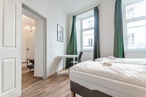 a bedroom with a bed and a desk and windows at Westbahnhof Kingbed 1BR Apt with ensuite washer in Vienna