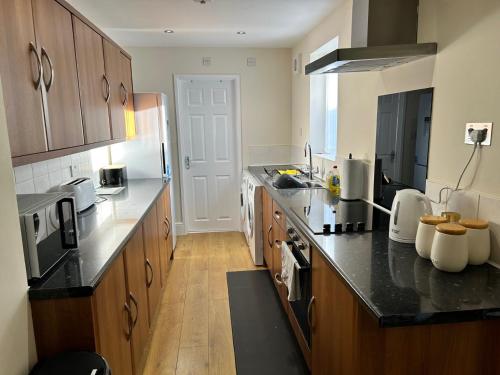 cocina con armarios de madera y encimera negra en Norton Serviced Apartments, en Stockton-on-Tees