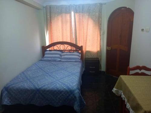 1 dormitorio con 1 cama con edredón azul y ventana en Posada de Mary, en Pisco