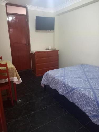 - une chambre avec un lit, une commode et une télévision dans l'établissement Posada de Mary, à Pisco