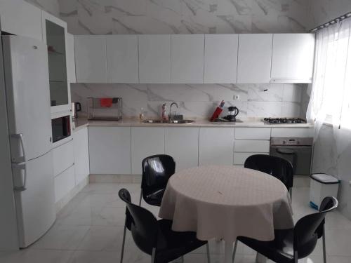 een keuken met een tafel en stoelen en een keuken met witte kasten bij chez Lourdes in Assomada