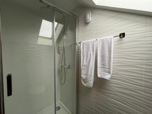uma casa de banho com chuveiro e toalhas brancas em Casas da Corujeira 2 no Porto