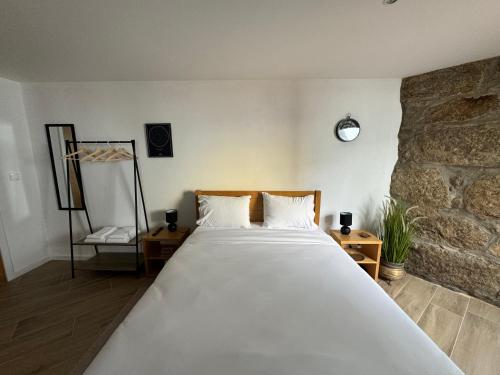 Cama grande en habitación con pared de piedra en Casas da Corujeira 2 en Oporto