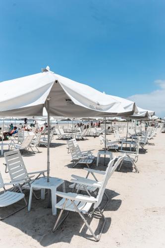 a group of chairs and umbrellas on a beach at Pool Ilha da Madeira Resort in Riviera de São Lourenço
