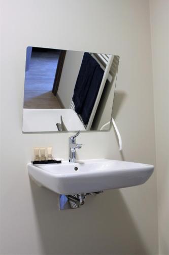 a white sink with a mirror on a wall at Bibi's Boerderij in Veurne