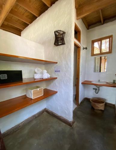 a bathroom with a sink and a shelf with towels at Bungalows Las Balsas in Máncora