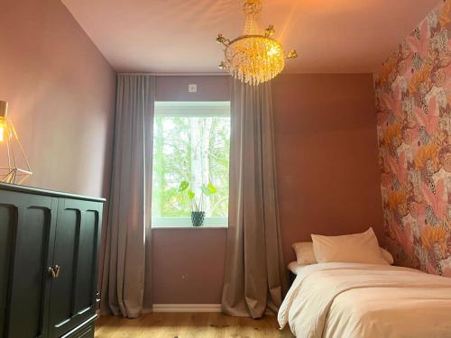 a bedroom with a bed and a window and a chandelier at Luxury Villa with Jacuzzi in Stockholm