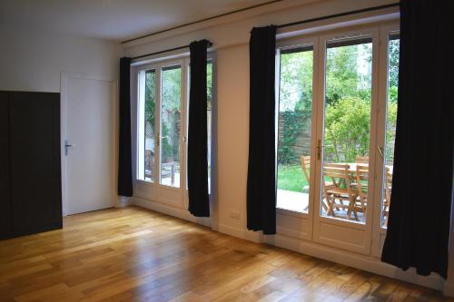 an empty room with large windows and wooden floors at Great apartment with private garden in Clichy