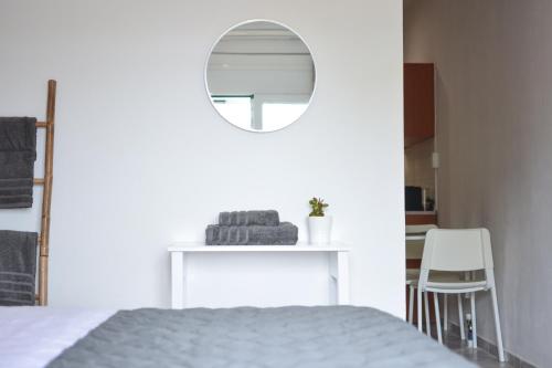 a white bedroom with a bed and a mirror at Daphne's studio 1 in Skiathos