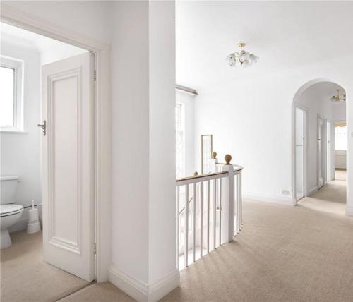 a white room with a toilet and a hallway at Large 5 Bedroom house in Finchley in Maida Vale