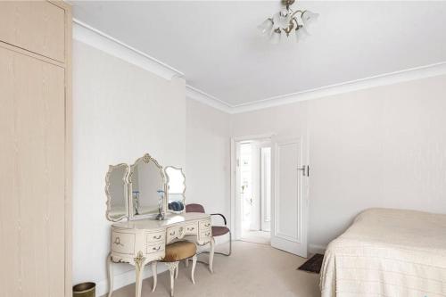 a white bedroom with a dressing table and a mirror at Large 5 Bedroom house in Finchley in Maida Vale