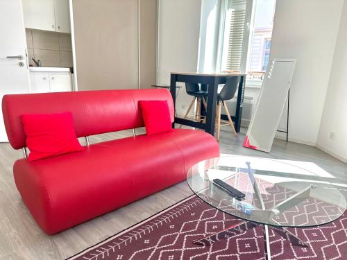 - un canapé rouge dans le salon avec une table en verre dans l'établissement The Love intimité au cœur du centre-ville, à Mulhouse