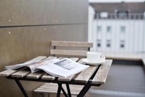 een houten tafel met een boek en een kopje koffie bij Moderne Apartments im Herzen von Osnabrück I private Tiefgarage I home2share in Osnabrück